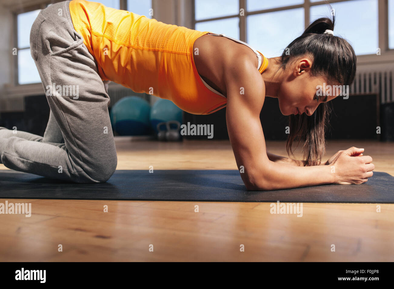 Mujer joven ejercer en fitness mat. Fuerte joven atleta femenina haciendo core ejercitarse en el gimnasio. Foto de stock