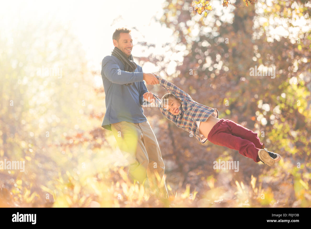 Padre spinning hijo entre hojas de otoño Foto de stock
