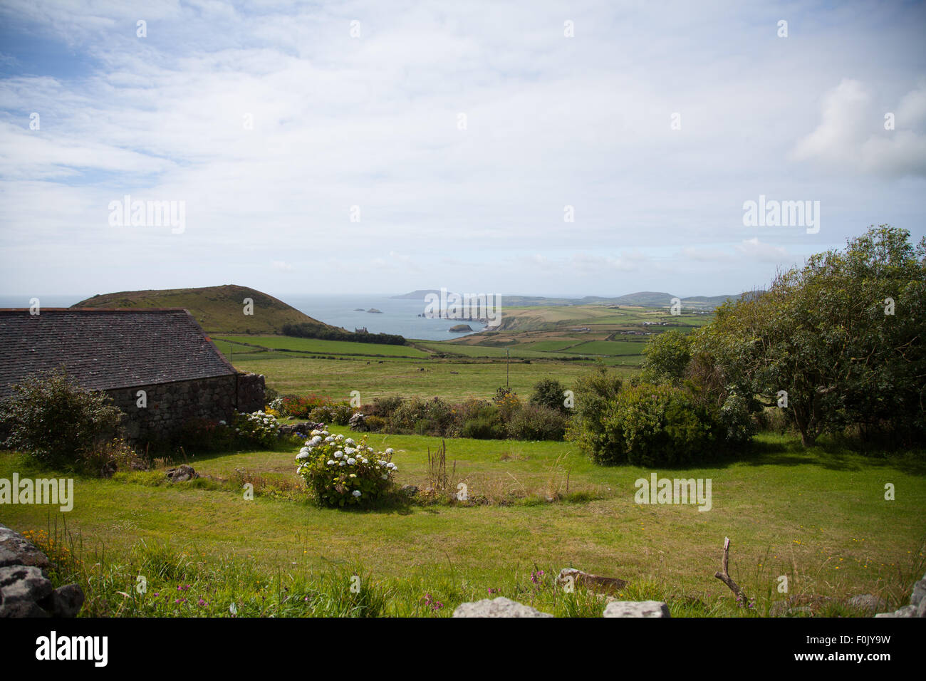Una vista de Carreg Lefain Rhiw, a través de campos a Penarfynydd con el mar y Ynys Enlli en la distancia en un día de verano Foto de stock