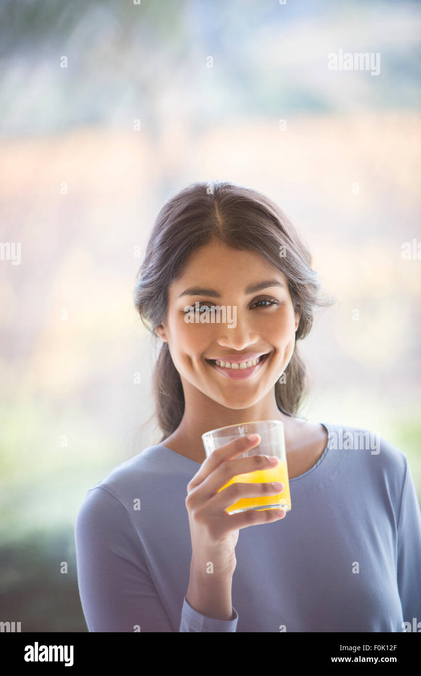 Retrato mujer sonriente beber jugo de naranja Foto de stock