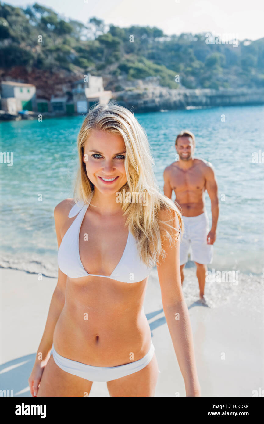 España, Mallorca, mujer sonriente en bikini en la playa con un hombre en  segundo plano Fotografía de stock - Alamy
