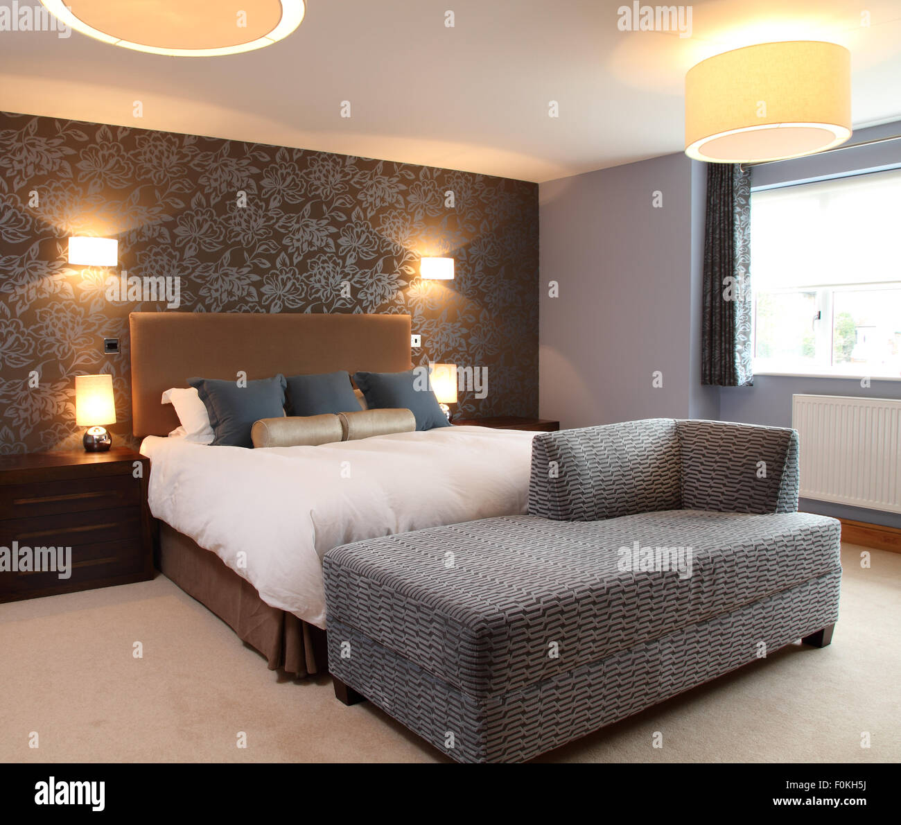 Dormitorio moderno con apliques lámparas de mesa lateral.Acolchado cabecero color camello.Brown papel tapiz con diseño de flor de pared gris Fotografía de stock - Alamy