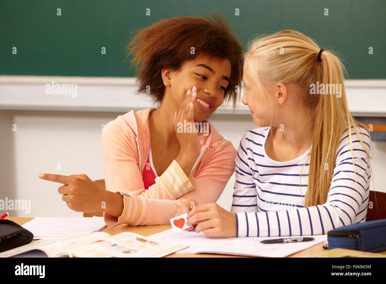 Dos niñas susurran sobre una carta de amor Foto de stock