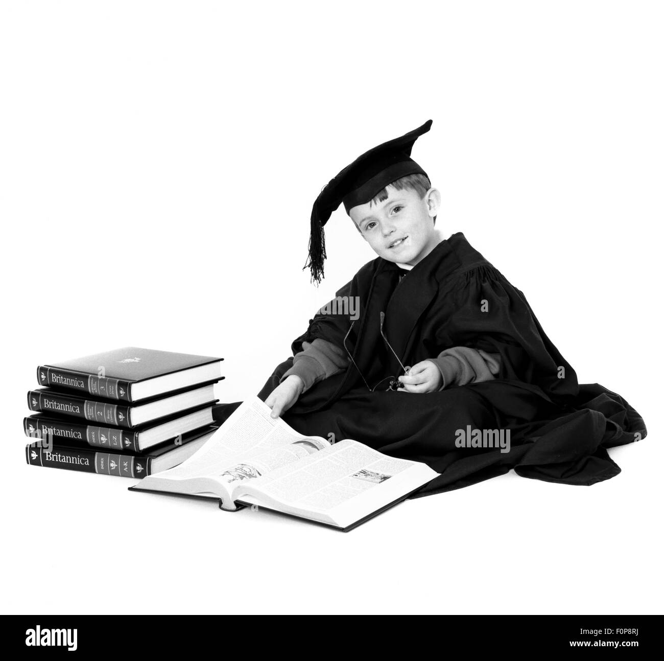 Joven vestida con toga y birrete leyendo Encyclopaedia Britannica Foto de stock