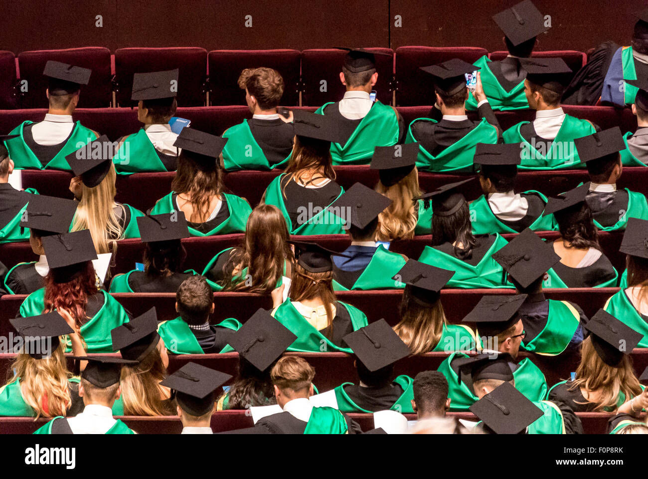 Vista trasera de los graduados a la espera de la presentación de los títulos en el día de graduación Foto de stock