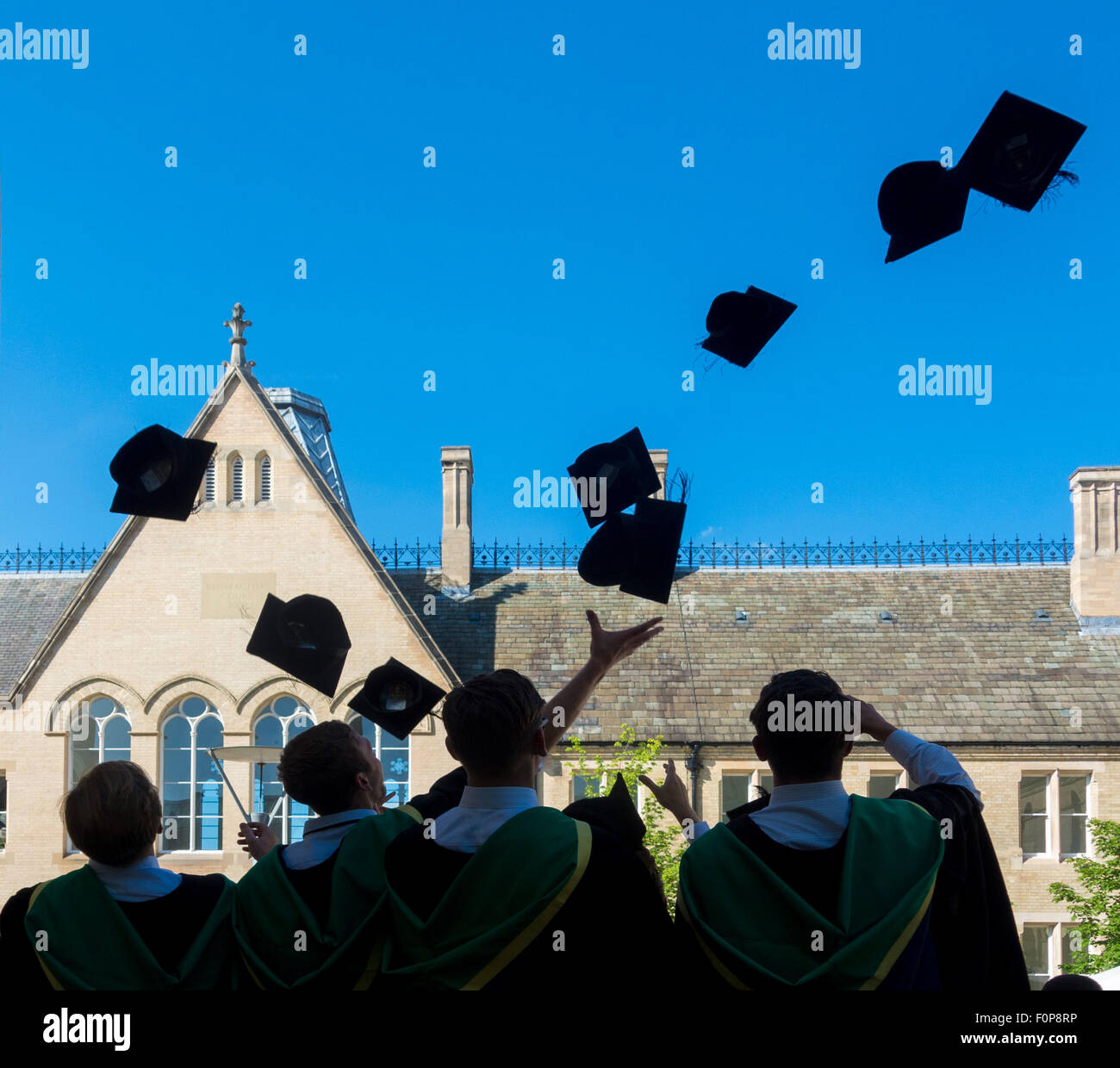 Vista trasera de los nuevos graduados celebrando lanzando morteros juntas en el aire en el día de graduación Foto de stock