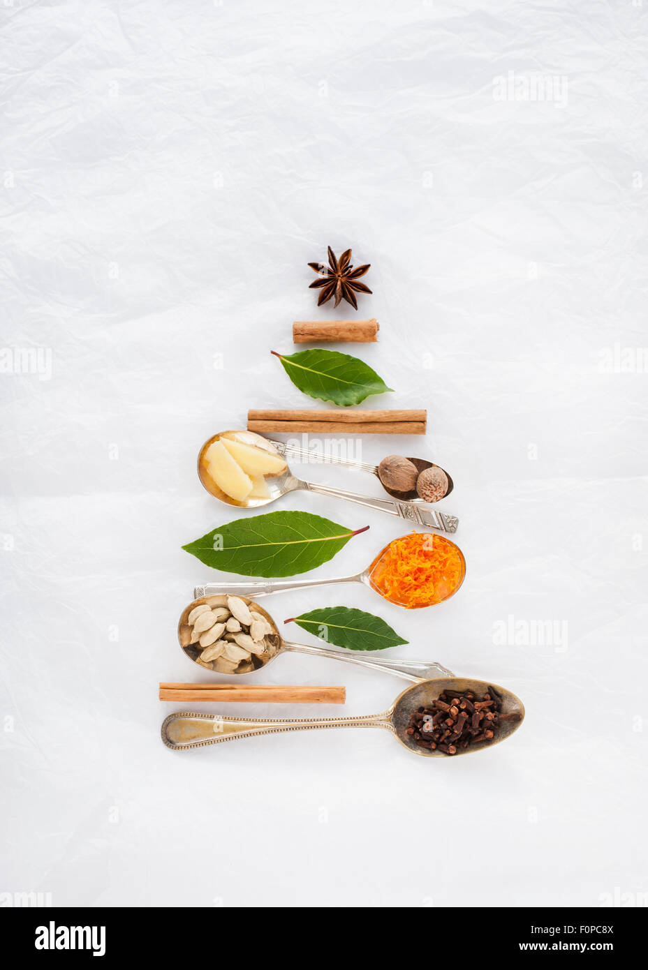 Una forma de árbol de Navidad hecho con cucharas y especias canela nuez moscada anís estrella laurel clavo Cardamom pods jengibre cáscara de naranja Foto de stock