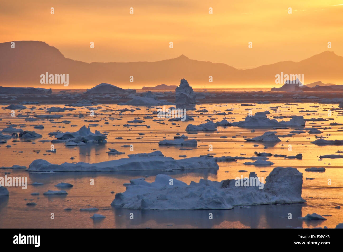 Sol de medianoche y icebergs en la bahía Disko, Ilulissat, Groenlandia occidental Foto de stock