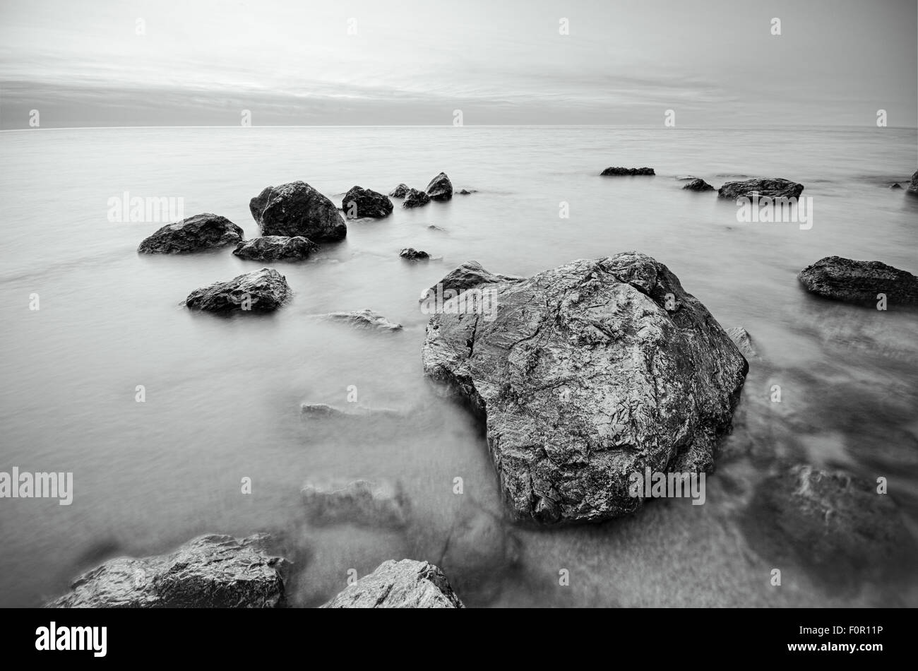 Fotografía en blanco y negro de piedras en la playa las rocas en la costa. Foto de stock