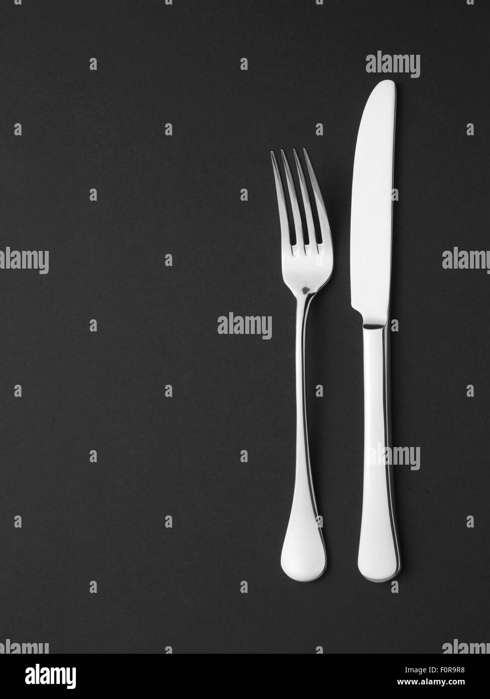 Cuchillo y tenedor presentados sobre fondo negro para gran restaurante de mercado Foto de stock