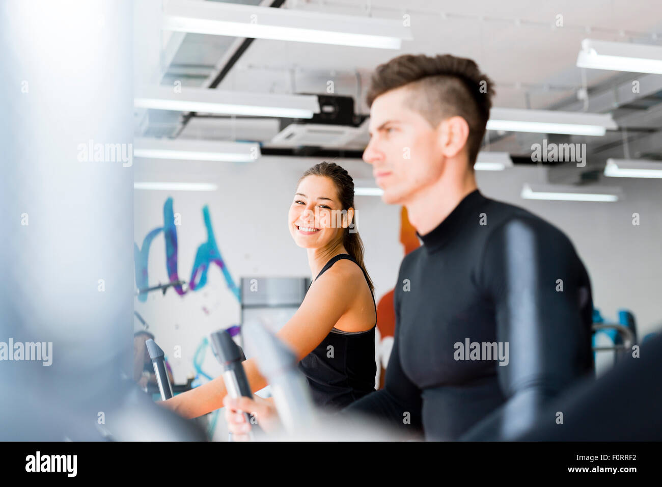 Grupo de personas jóvenes y sanos trabajaban sobre un entrenador elíptico en un gimnasio Foto de stock