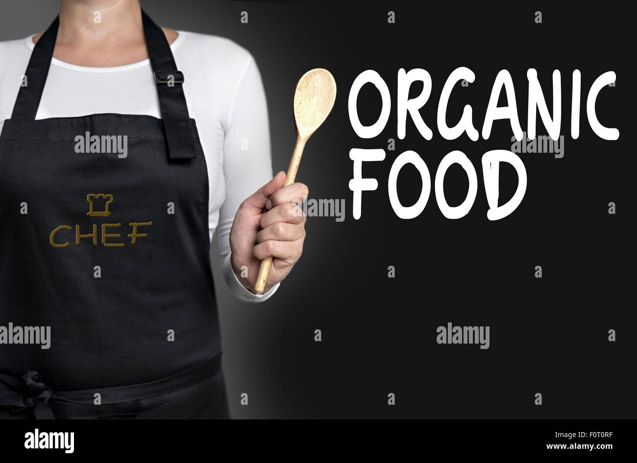 Los alimentos orgánicos chef sosteniendo una cuchara de madera de fondo. Foto de stock