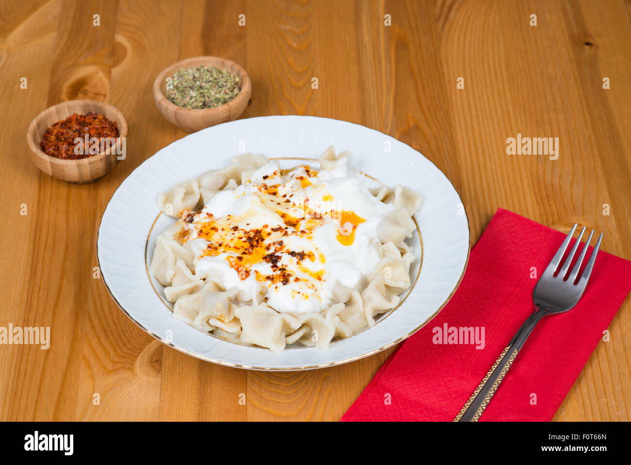 Manti turco (raviolis) en la placa con la mantequilla, la pimienta roja salsa, yogur y menta Foto de stock