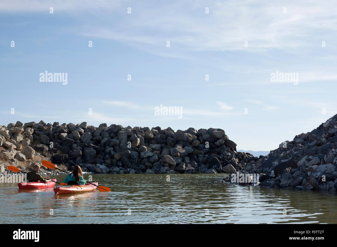 Vista trasera de palistas sentado sobre el agua en kayaks hacia las rocas, Gran Lago Salado, Utah, EE.UU. Foto de stock