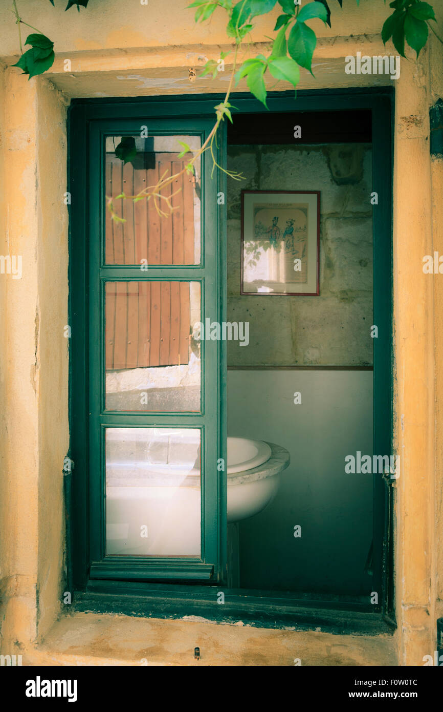 Antiguo parcialmente abierta ventana con vista parcial del lavabo sin gente Foto de stock