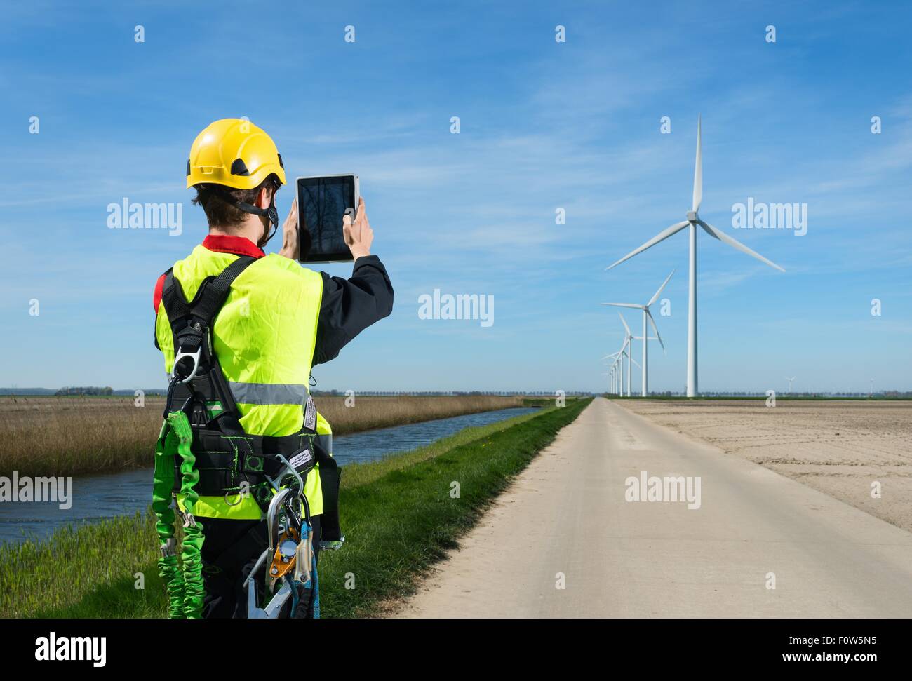 Obrero de mantenimiento tomando la fotografía de parque eólico utilizando tablet digital, Biddinghuizen, Flevoland, Holanda Foto de stock