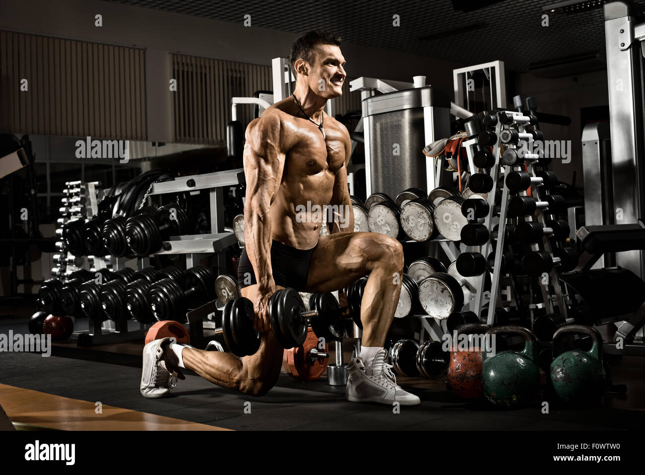Muy power athletic guy , ejecutar el ejercicio con pesas en el gimnasio Foto de stock
