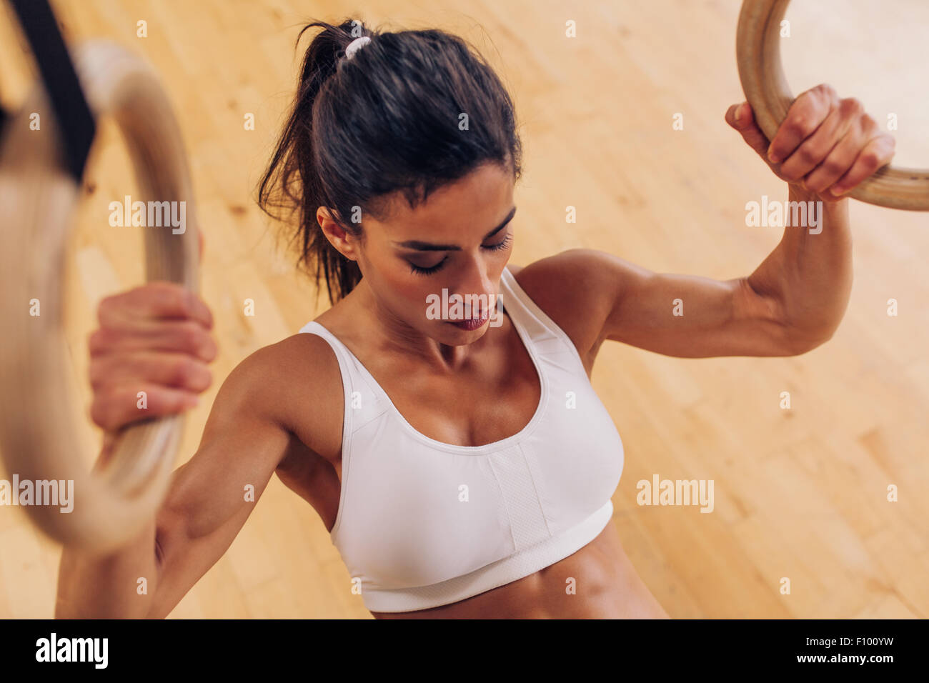 Imagen de fuerte joven haciendo pull-ups ejercicio usando anillos de gimnasia en el gimnasio. Foto de stock