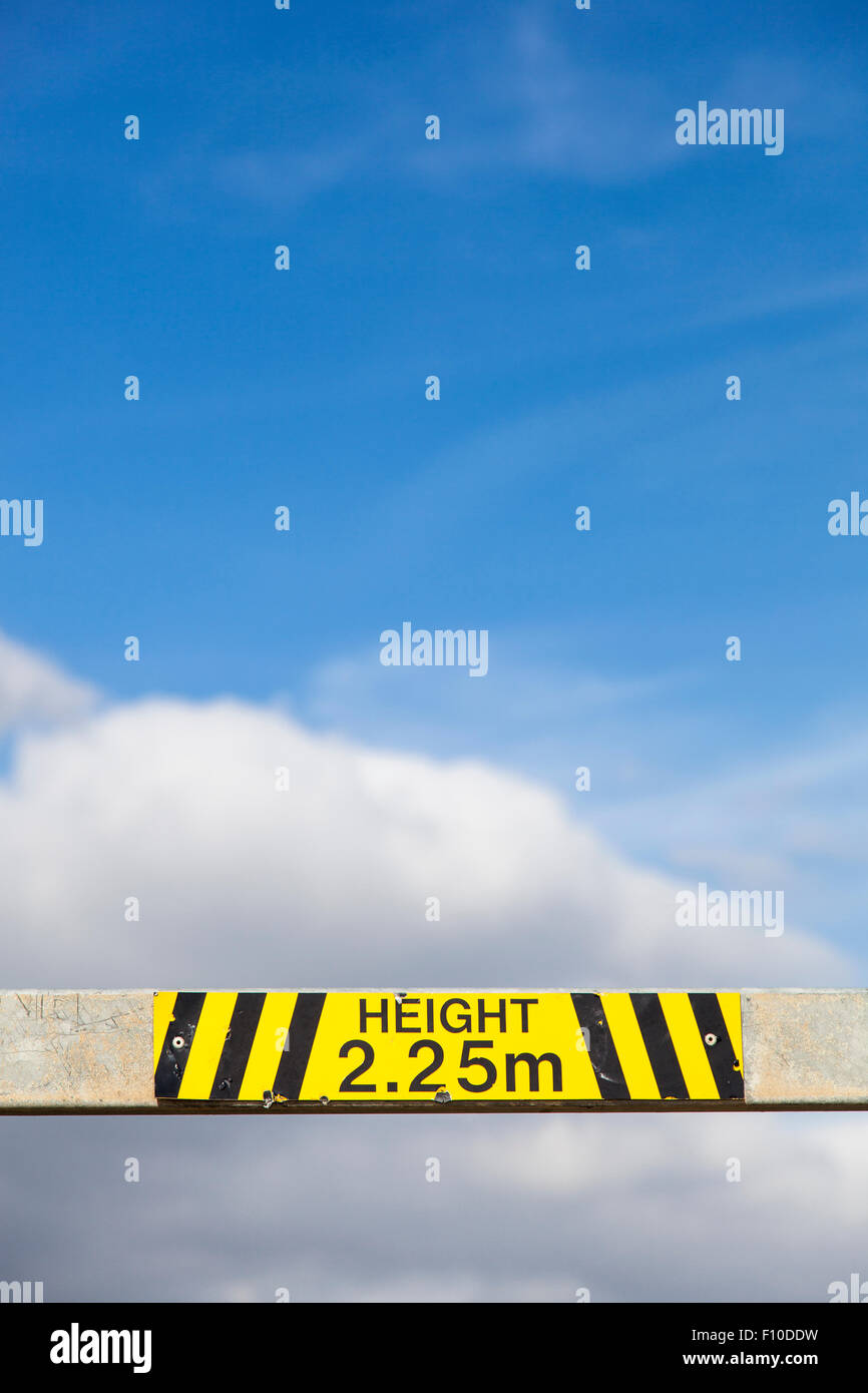 Parte de una barrera metálica para la limitación de la altura de un aparcamiento, que muestra el límite 2,25 m en amarillo y negro. Foto de stock