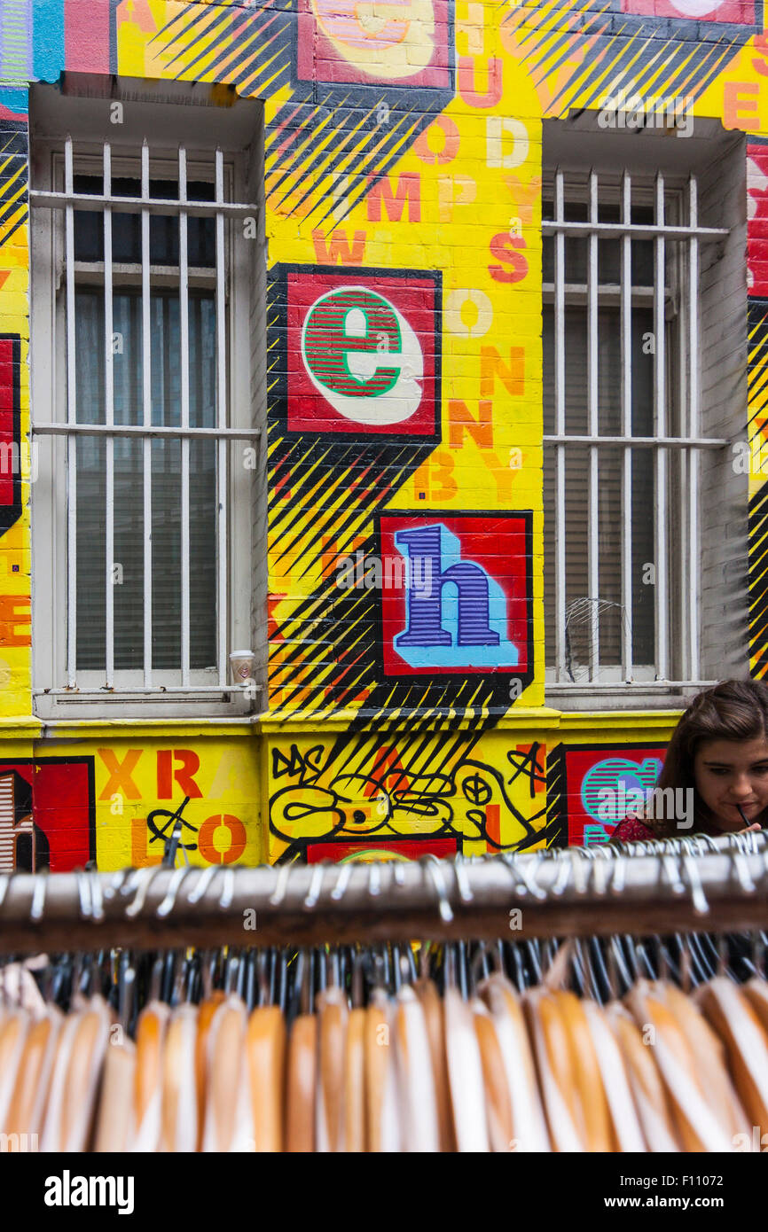 Chica de compras en frente de un Ben Eine mural, Petticoat Lane market, Londres, Inglaterra, Reino Unido Foto de stock