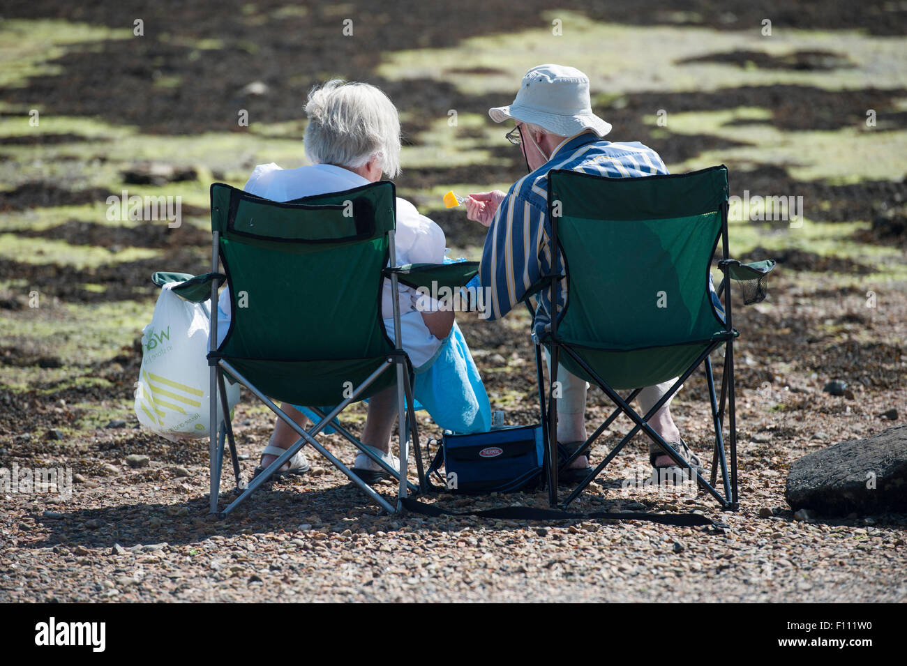 Generación anterior dos personas disfrutar de un picnic junto al mar en el sol de verano Foto de stock
