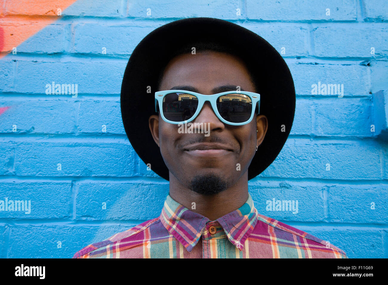 El hombre de negro con gafas de sol cerca de paredes coloridas Foto de stock