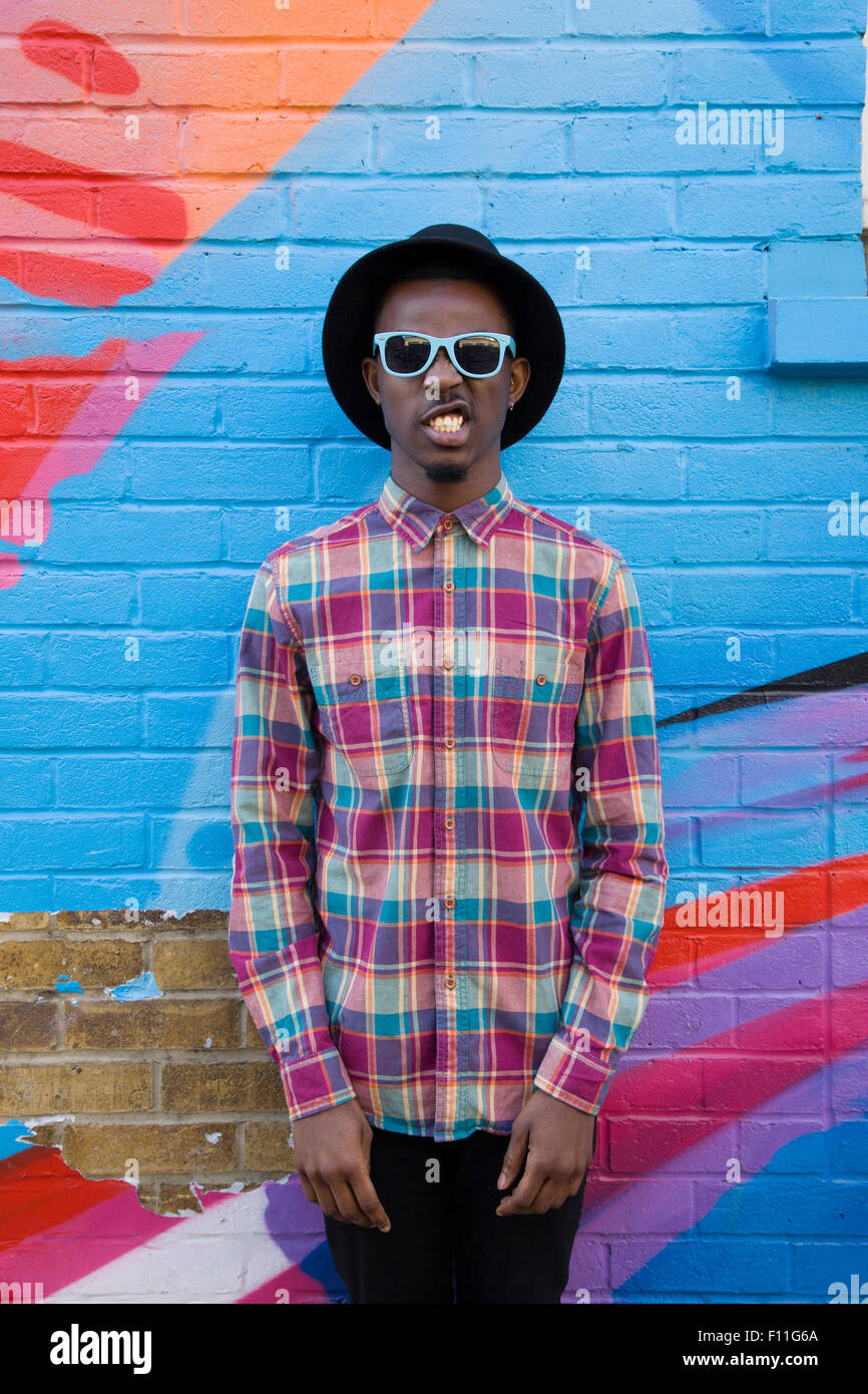 El hombre de negro con gafas de sol cerca de paredes coloridas Foto de stock