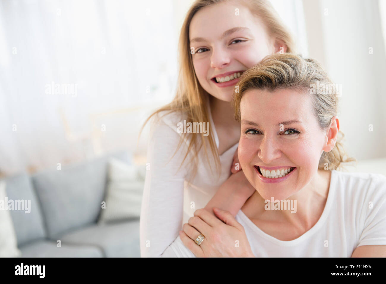 Madre e hija caucásica sonriendo en la sala de estar Foto de stock