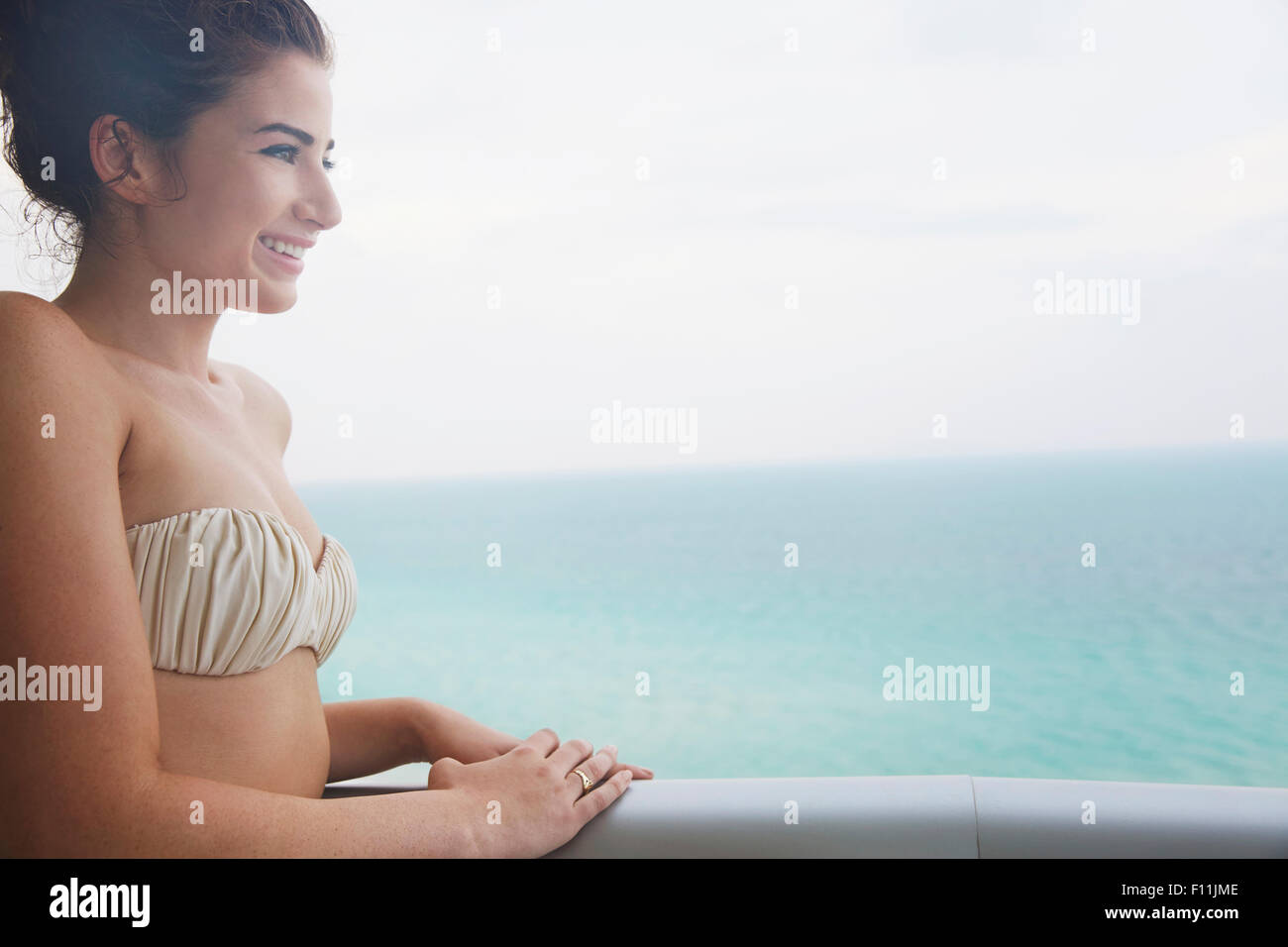 Mujer de raza mixta con vistas al océano desde el balcón Foto de stock