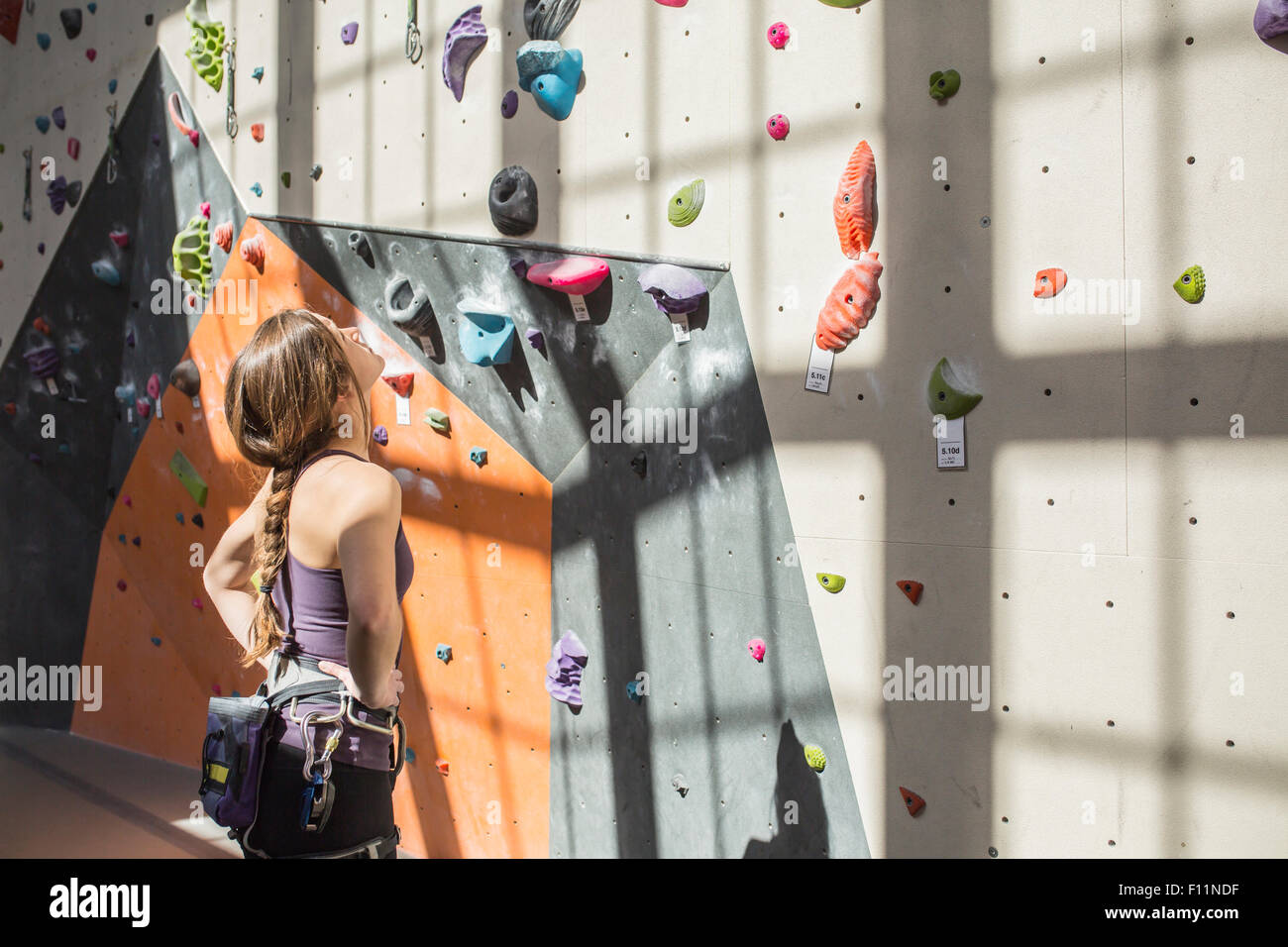 Atleta examinar pared de roca en el gimnasio Foto de stock
