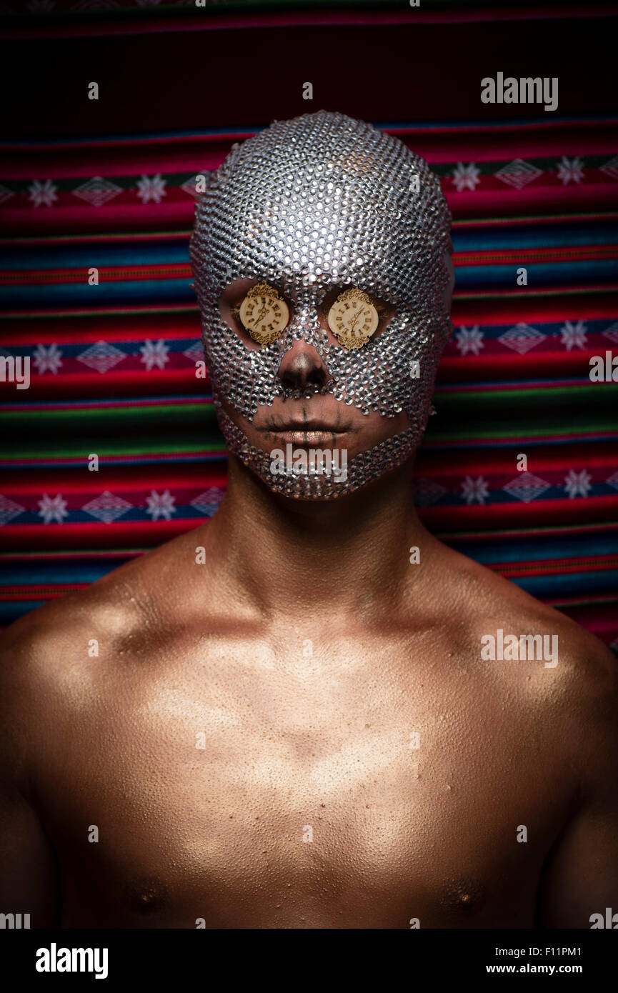 'Día de los Muertos' tema vertical - un hombre joven con lentejuelas de cristal pegado a su cara y mini reloj caras sobre sus ojos pegados Foto de stock