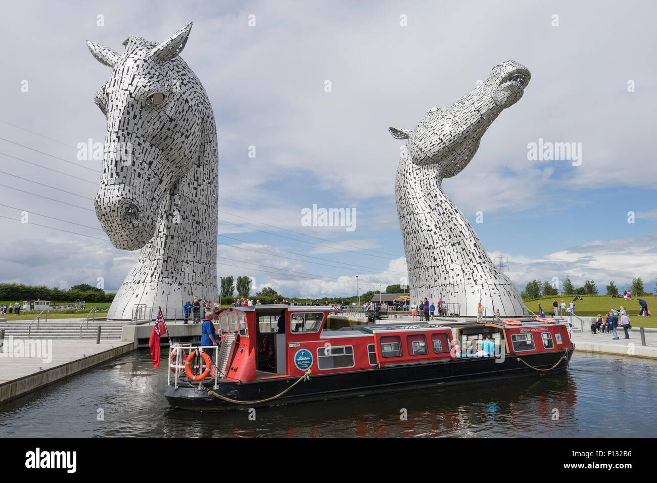 Los Kelpies escultura de dos caballos cruzando canal Forth and Clyde y turístico en el canal boat Helix Park,Falkirk, Escocia Foto de stock