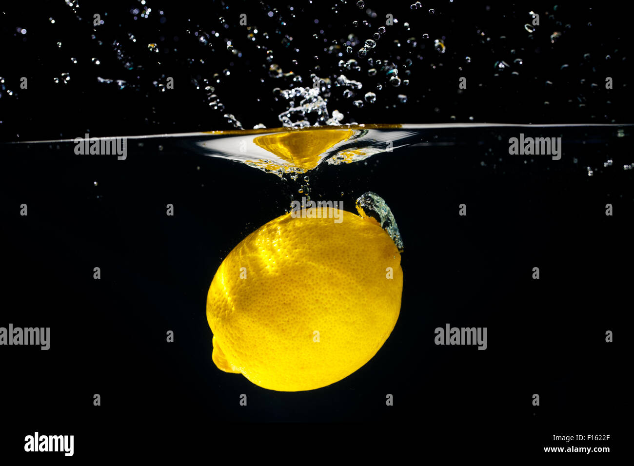 Limón amarillo sobre negro salpicaduras de agua Foto de stock