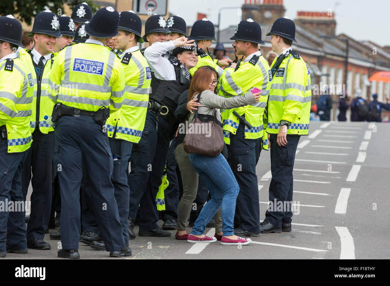 Londres, Reino Unido. El 30 de agosto de 2015. Una mujer policía plantea para un selfie con juerguistas. El Carnaval de Notting Hill comienza con los desfiles en el Día del Niño. Foto: bas/Alamy Live News Foto de stock