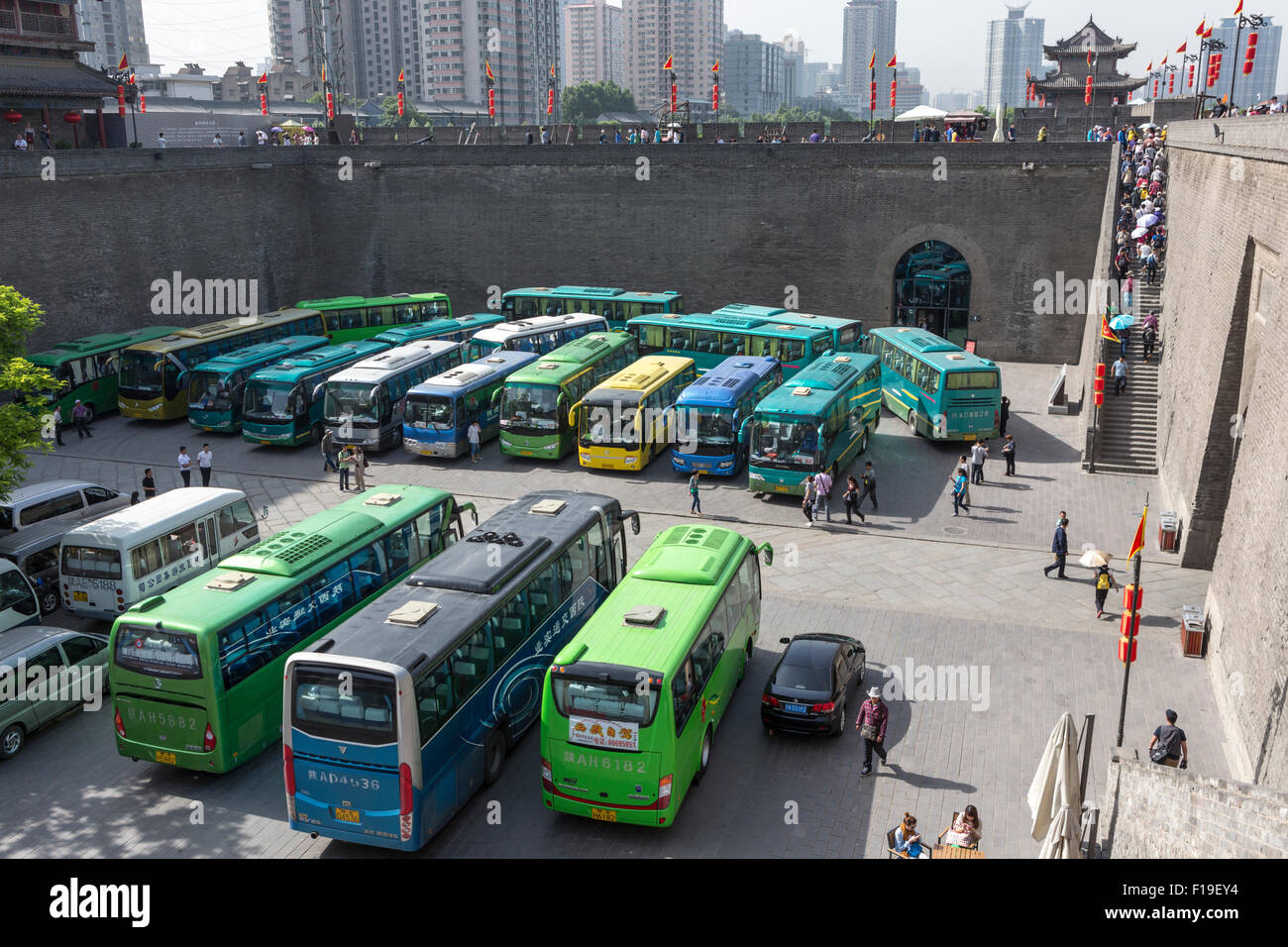 Puerta oriental de la muralla de la ciudad de Xi'an, con un puntaje de autobuses turísticos y muchos turistas en las escaleras o en la pared. Foto de stock