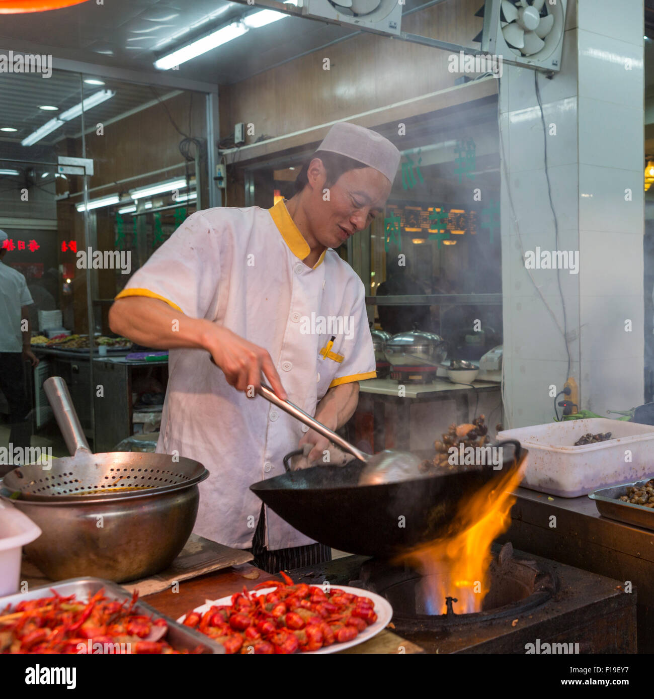 Cocinero prepara alimentos sobre flaming wok en acera puesto de comida  rápida en el barrio musulmán de Xi'an en China Fotografía de stock - Alamy
