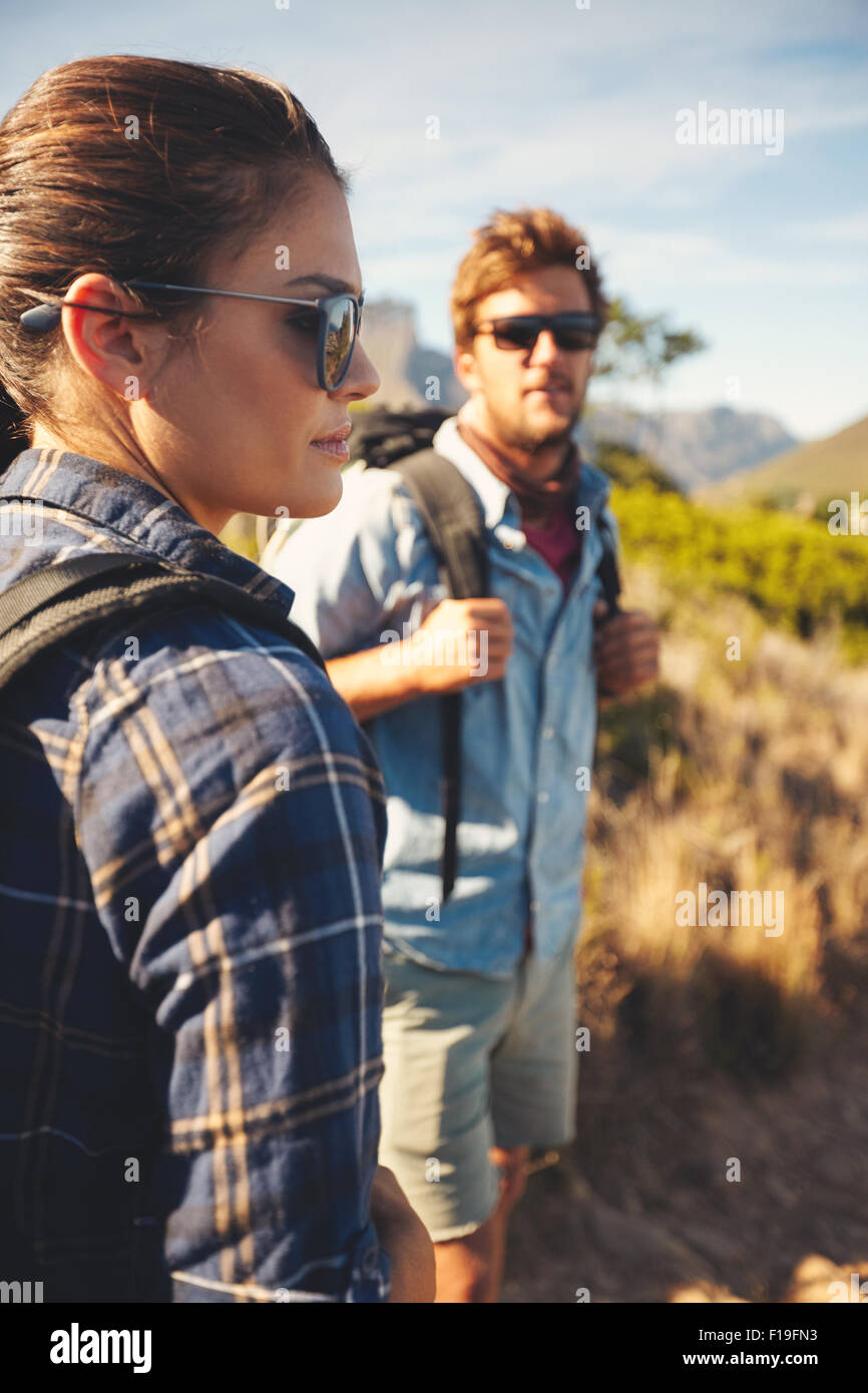 Pareja en alza en el campo. Mujer de pie en la parte delantera mirando a una vista con el hombre en el fondo. Excursión pareja caucásica en natu Foto de stock