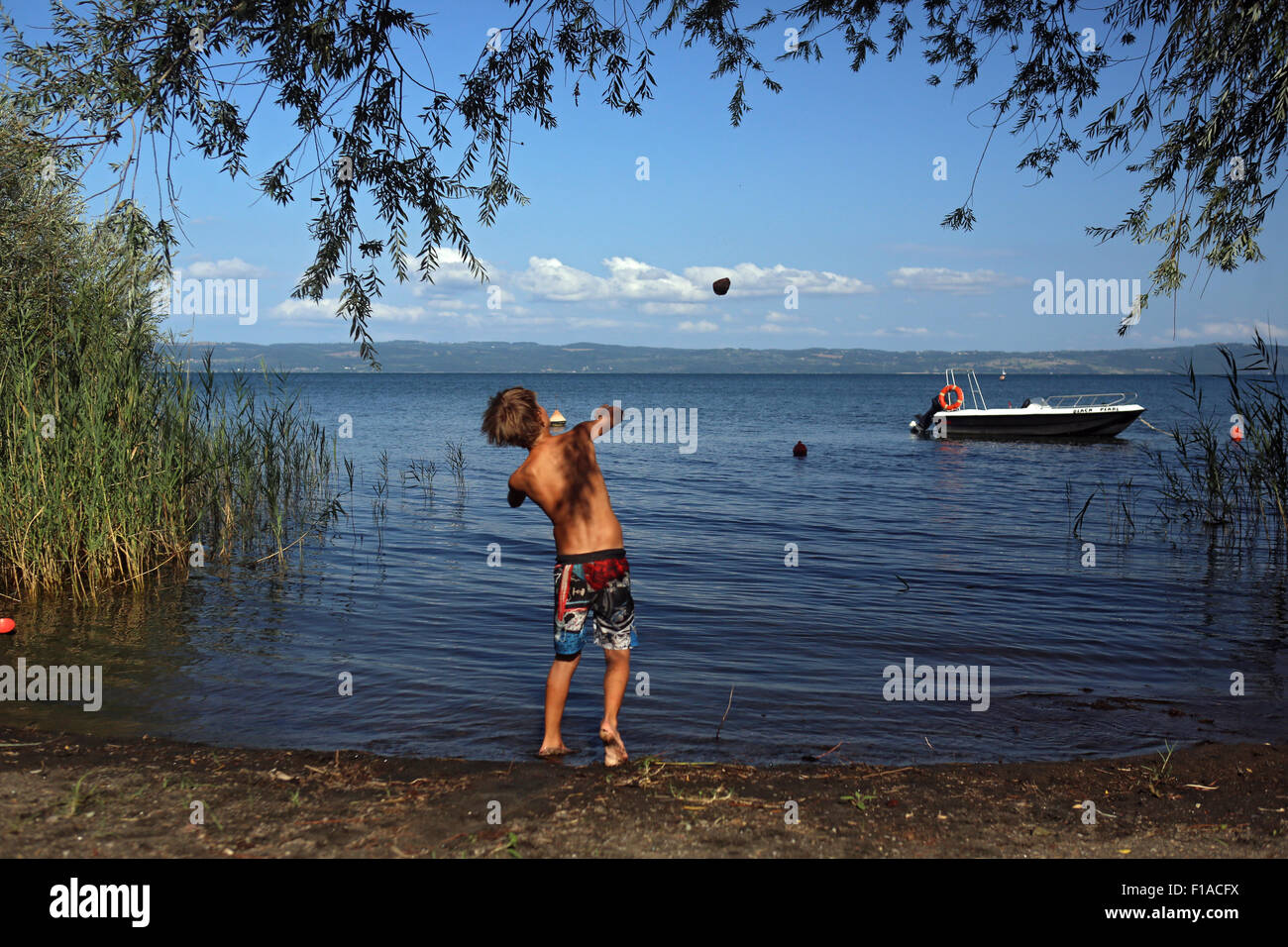 Bolsena, Italia, boy lanza una roca en el lago de Bolsena Foto de stock
