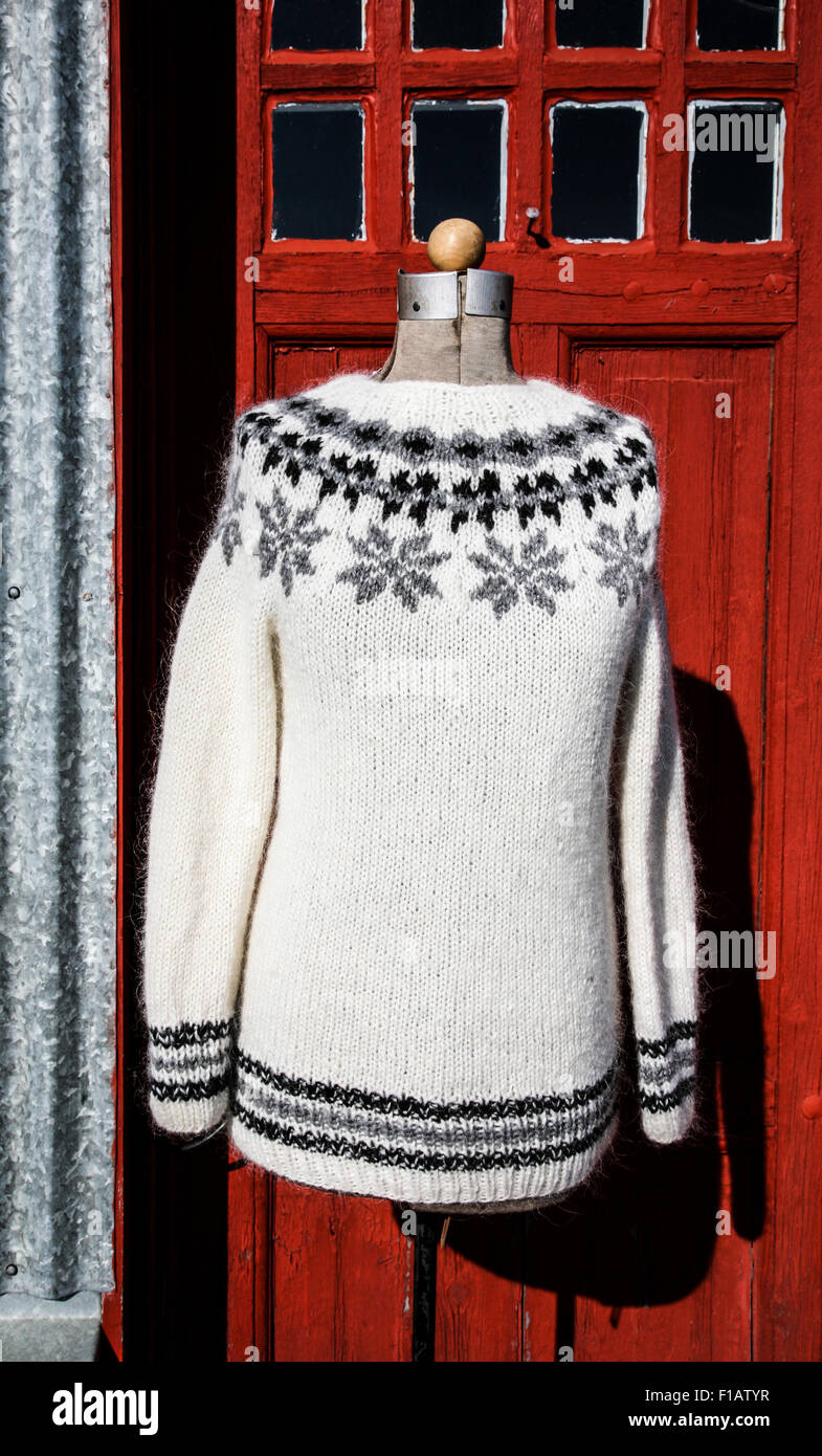 Tejidos artesanales de lana suéter islandés con un patrón de copo de nieve  con un telón de fondo de la puerta roja en Islandia, Europa islandés  woolens poinsettia patrón Fotografía de stock -