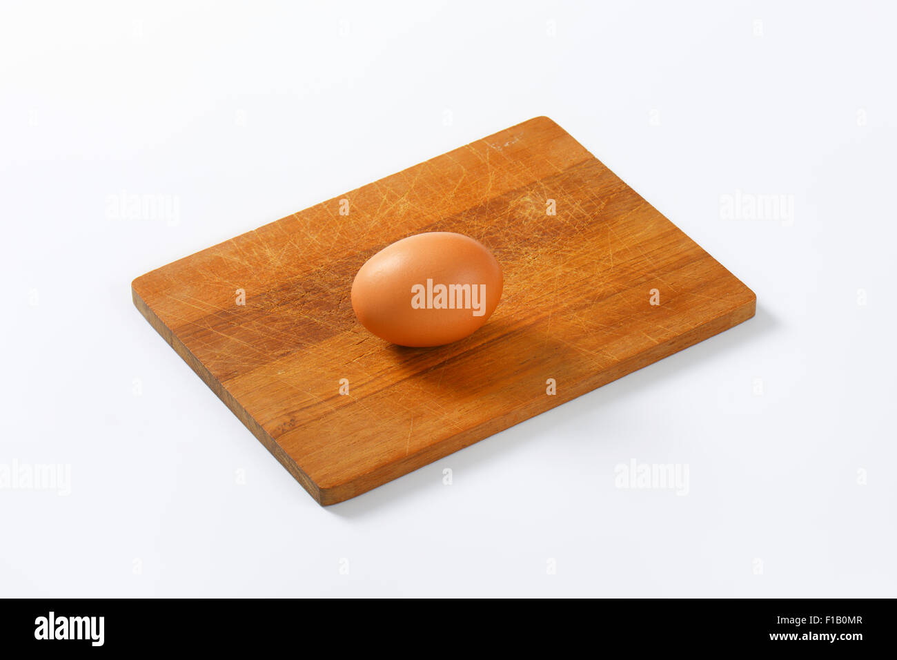 Huevo sobre tabla de cortar de madera Foto de stock