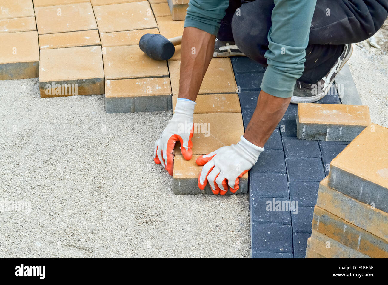 Primer plano de las manos de un trabajador durante la pavimentación de la acera Foto de stock