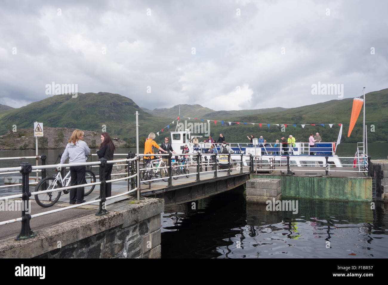 Los pasajeros con embarque bicicletas de la dama del lago, barco de recreo a Stronachlachar Pier, Loch Katrine, Scotland, Reino Unido Foto de stock