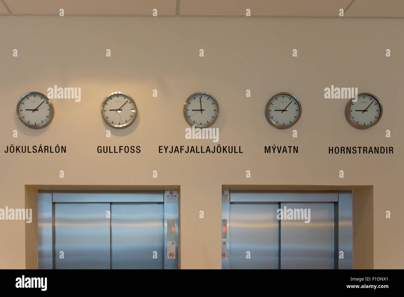 Relojes en el vestíbulo del hotel Klettur en Reikiavik mostrando diferentes tiempos en una variedad de pueblos y aldeas De Islandia Foto de stock