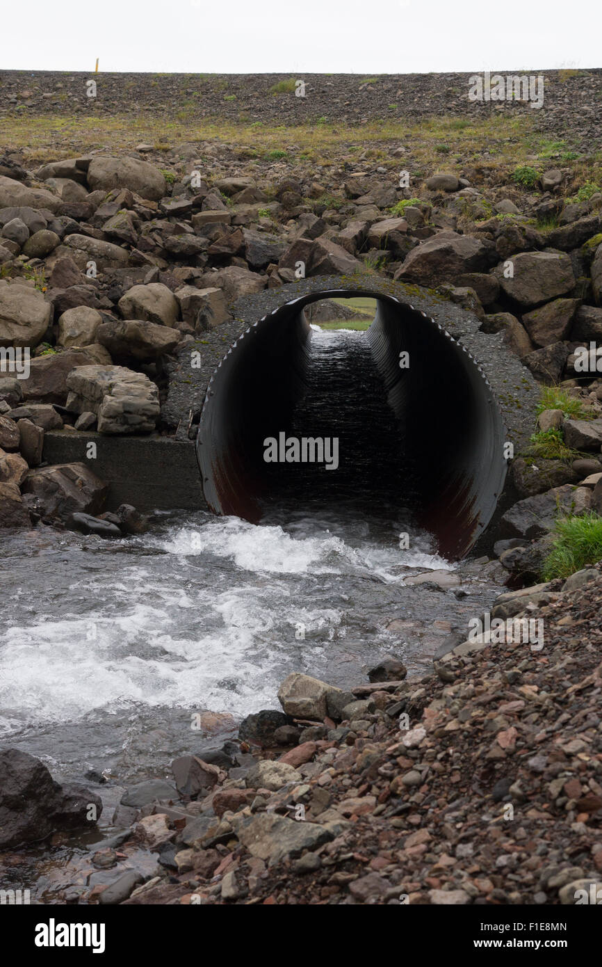 Una alcantarilla de metal corrugado - un tubo de drenaje para la superficie Agua - corriendo bajo la autopista Ruta 1 en Islandia Foto de stock