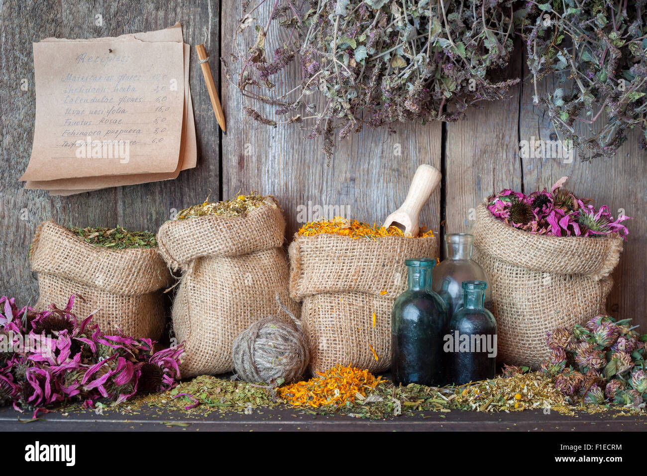 Hierbas curativas en sacos de arpillera, cerca de paredes de madera, la medicina herbaria. Foto de stock