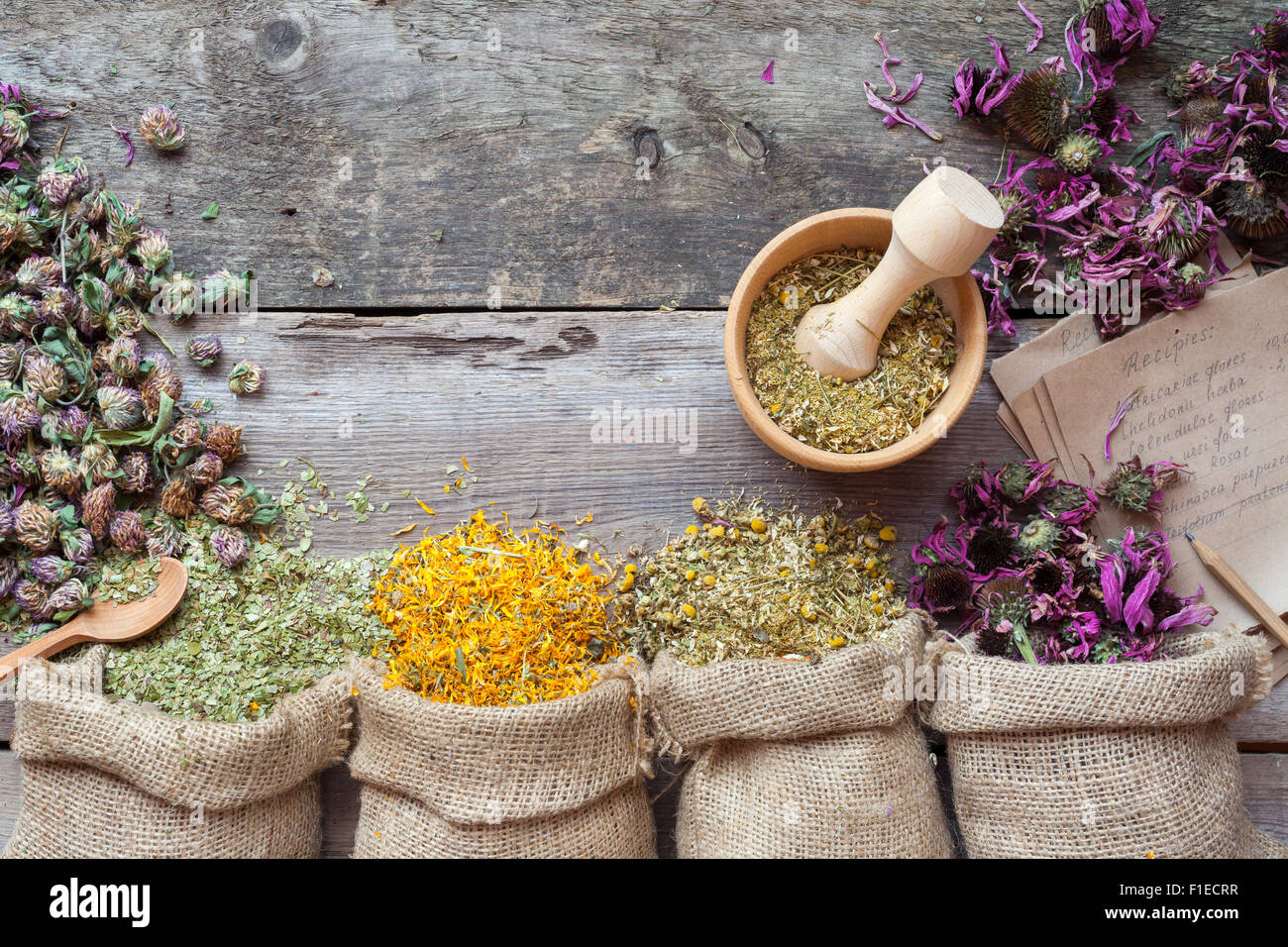 Hierbas curativas en sacos de arpillera, mortero de madera y recetas, la medicina herbaria. Vista desde arriba. Foto de stock