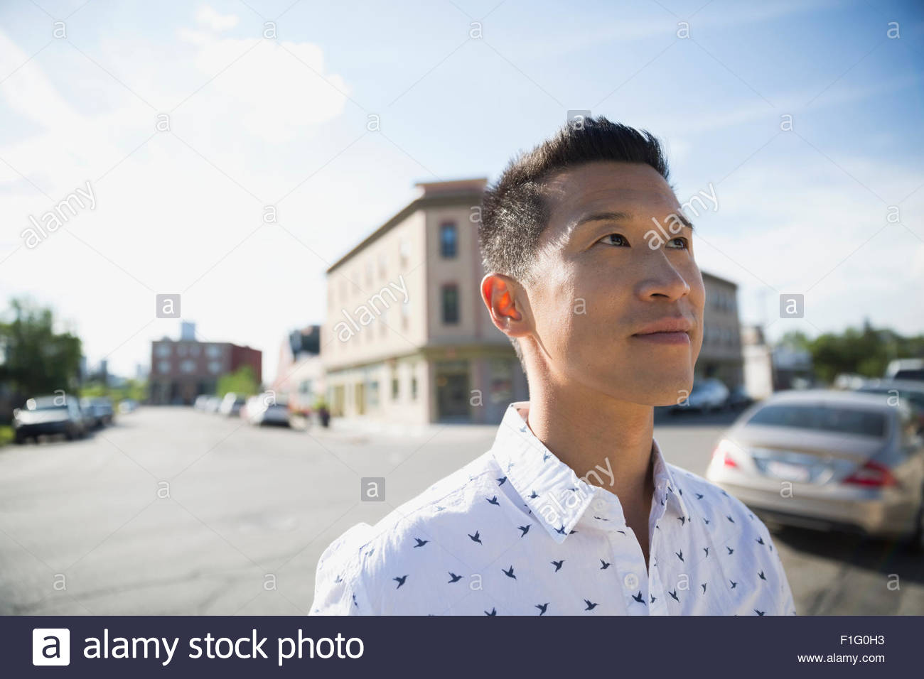 Pensativo hombre mirando hacia arriba en la calle soleada, Foto de stock