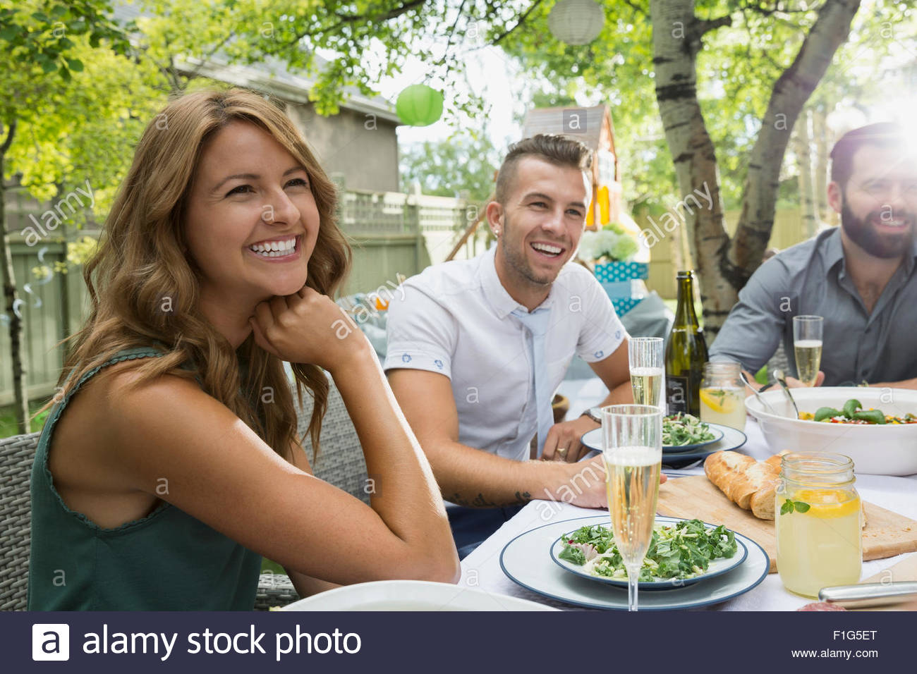 Sonriendo amigos disfrutando garden party almuerzo Foto de stock