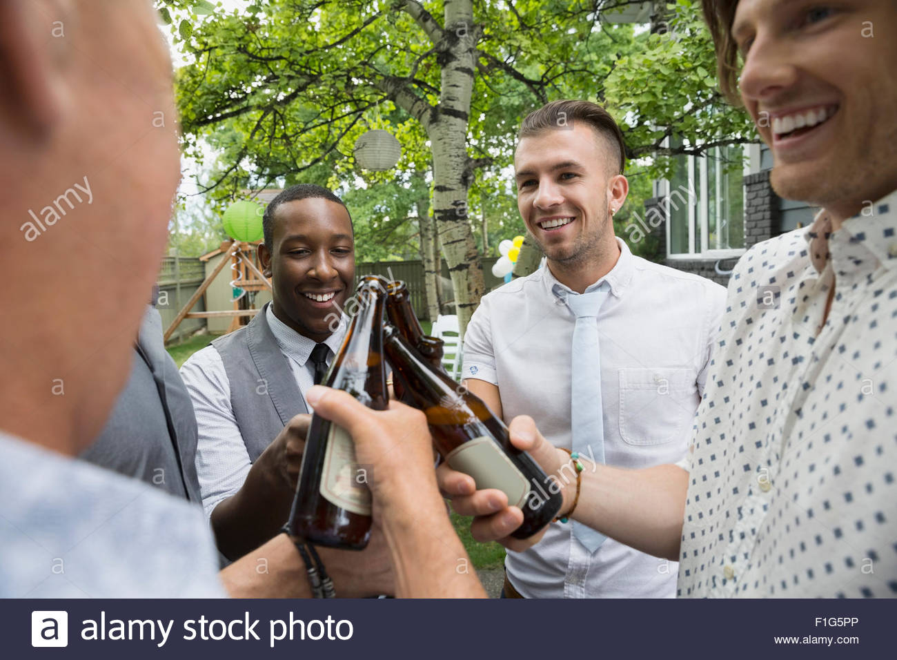 Los hombres de tostar los vasos de cerveza en el garden party Foto de stock