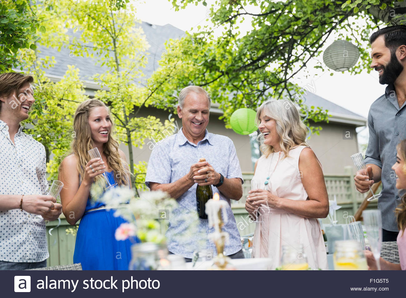 El hombre la apertura de botella de champán en el garden party almuerzo Foto de stock